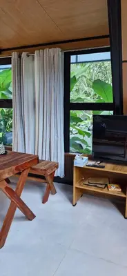 a room with a table and a bench and a window at Cherry Blossoms Chalet in Kozhikode