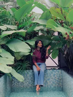 a woman sitting on a wall with plants at Cherry Blossoms Chalet in Kozhikode