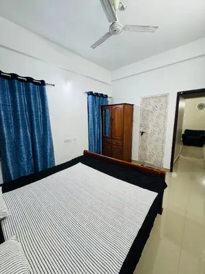 a bedroom with a bed with blue curtains at Harmony Nests in Thattakād