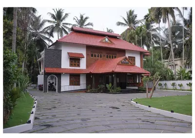 a house with a red roof and a driveway at Dr Indulekhas Ayurvedic Wellness & Rejuvenation in Tellicherry
