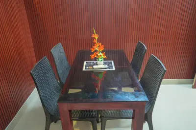a wooden table with chairs and a vase with flowers on it at Mayflower Family Lounge -Cochin Airport in Nedumbassery