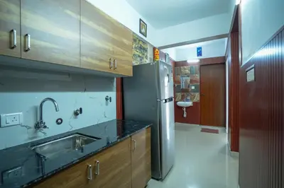 a kitchen with a sink and a stainless steel refrigerator at Mayflower Family Lounge -Cochin Airport in Nedumbassery