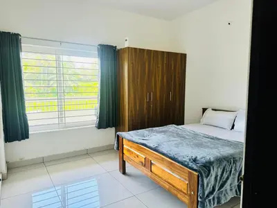 a bedroom with a bed and a wooden cabinet at Jayasviinn Coorg in Virajpet
