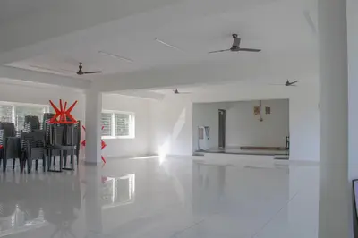 a white room with black chairs and a white floor at Jayasviinn Coorg in Virajpet