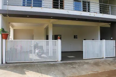 a white gate in front of a house at Jayasviinn Coorg in Virajpet