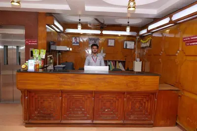a man standing behind a bar in a restaurant at Sakthi Hotel in Pollāchi