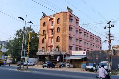 a man riding a bike in front of a pink building at Sakthi Hotel in Pollāchi