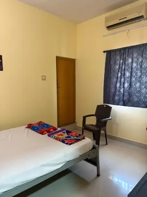 a bedroom with a bed and a chair and a window at AJ GrandInn in Podanūr