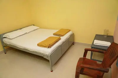 a small bedroom with a bed and a chair at AJ GrandInn in Podanūr