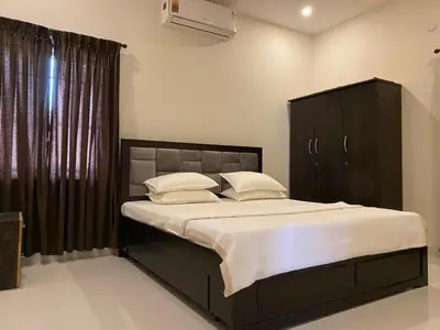 a bedroom with a large bed with white sheets and pillows at LBS Farmstay in Alāndurai