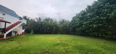 a yard next to a house with trees at LBS Farmstay in Alāndurai