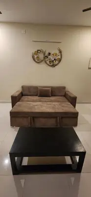 a brown couch in a room with a table at LBS Farmstay in Alāndurai