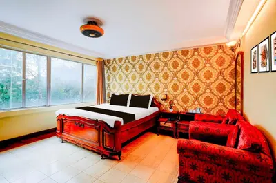 a bedroom with a bed and a red couch at Collection O Puthali Park Near Mysuru Railway Station in Mysore