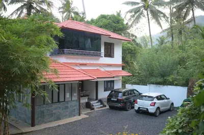 two cars parked in a parking lot in front of a house at Cardamom cottage in Periya