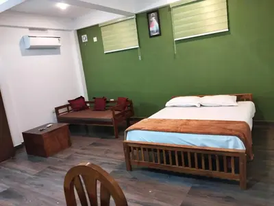 a green room with a bed and a chair at DB GUEST HOUSE ARIMPUR - Unmarried couples and Stag groups not allowed in Trichūr