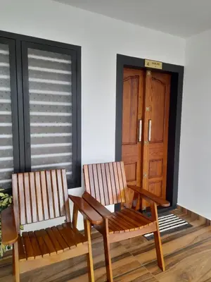 two wooden chairs sitting in front of a door at VGK Residency in Wayanad