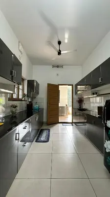 a large kitchen with black cabinets and a ceiling at Snehanilayam in Trichūr