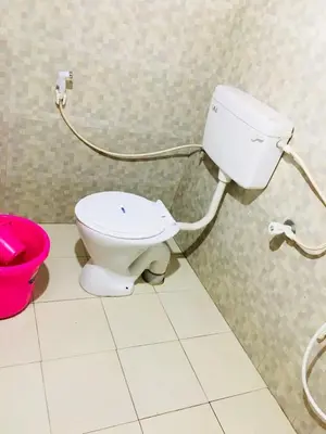 a bathroom with a toilet and a pink bucket at Vintage Breeze Home Stay in Madikeri