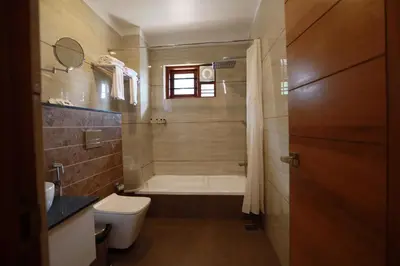a bathroom with a bath tub and a toilet at Devalokam Edappal in Edappāl