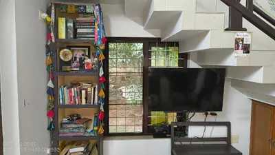 a living room with a tv and a book shelf at The Mangosteen Homestay in Kodanad