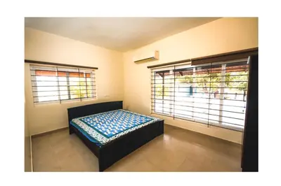 a bed in a room with two windows at Vetha farm in Aravakkurichchi