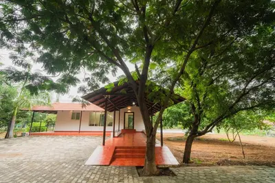 a small house with a tree in front of it at Vetha farm in Aravakkurichchi