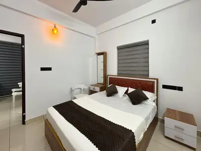 a bedroom with a large bed in a white room at Lakshmi Home in Trichūr