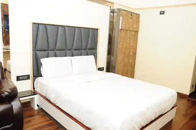 a bedroom with a large white bed with a black headboard at Vgrand in Ooty