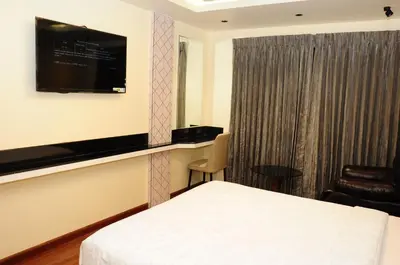 a hotel room with a bed and a flat screen tv at Vgrand in Ooty