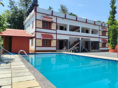 a building with a swimming pool in front of a building at Empire Life Pool Villa in Meenangadi