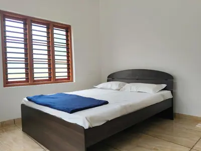 a bedroom with a bed with a blue blanket on it at Empire Life Pool Villa in Meenangadi