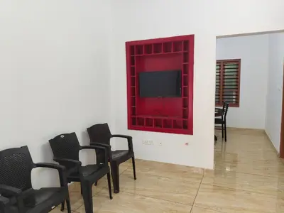 a room with chairs and a tv on a wall at Empire Life Pool Villa in Meenangadi