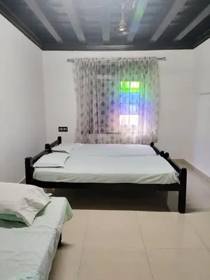 a bedroom with two beds and a window with a curtain at Thiruvambady Heritage Homestay in Trichūr
