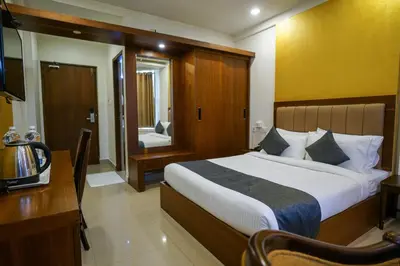 a bedroom with a bed and a desk and a television at Royal Plaza Glitz Inn in Kozhikode