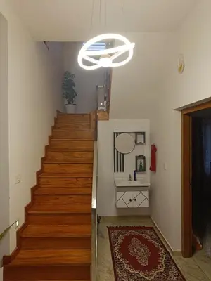 a hallway with a staircase with a white chandelier at La casona in Kottayam