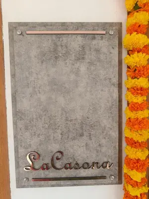 a sign for a restaurant with flowers around it at La casona in Kottayam