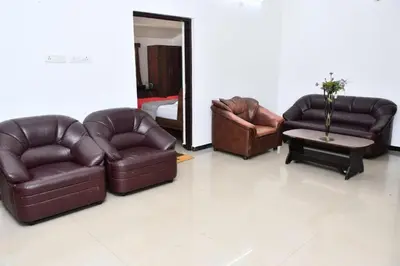 a living room with brown leather furniture and a bed at Classic Homestay Hills Ooty in Ooty