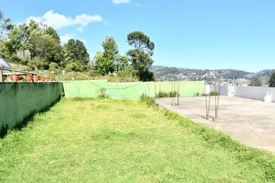 a yard with a green fence and a field at Classic Homestay Hills Ooty in Ooty