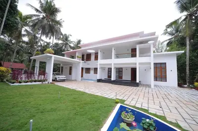 a large white house with a lawn in front of it at Village Pavilion in Tellicherry