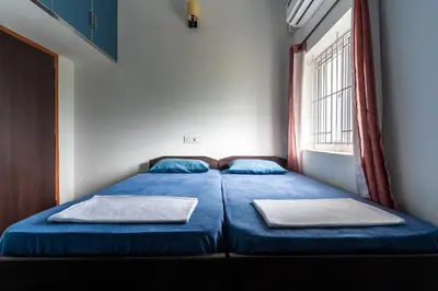 a bedroom with a bed with blue sheets and a window at Meenakshi residency in Alāndurai