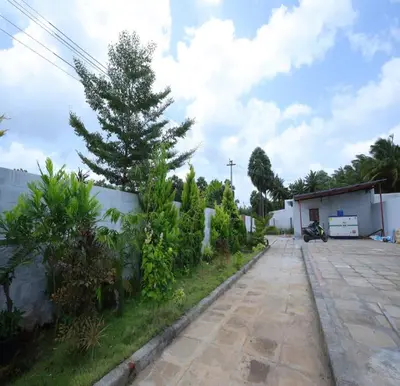 a driveway in front of a house with a tree at The Canalway Inn in Pollāchi