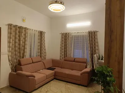 a living room with a brown couch and curtains at La-Casona in Kottayam
