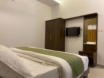 a bedroom with a bed and a cabinet with a tv at Wayanad Mona Villa in Wayanad