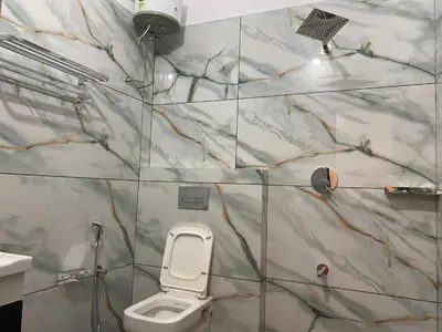 a bathroom with a white toilet and marble walls at Wayanad Mona Villa in Wayanad