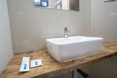 a bathroom with a white sink and a mirror at Cross Roads Inn in Coimbatore