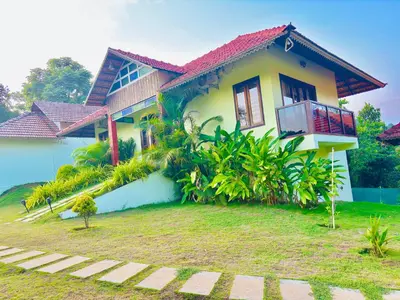 a yellow and white house with a yard at Vaca Vibes Resorts in Koroth