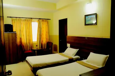 a hotel room with two beds and a window at Suvarna Residency in Mysore