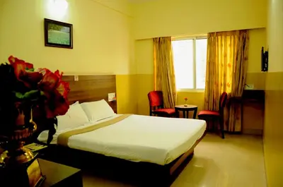 a hotel room with a bed and a window at Suvarna Residency in Mysore