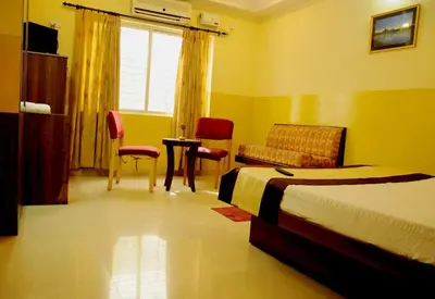 a bedroom with a bed and a couch and a table at Suvarna Residency in Mysore