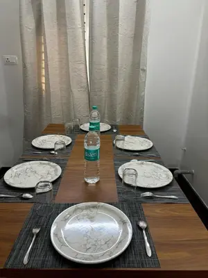 a table with plates and a bottle of water on it at Maitree Serenity Farm Stay